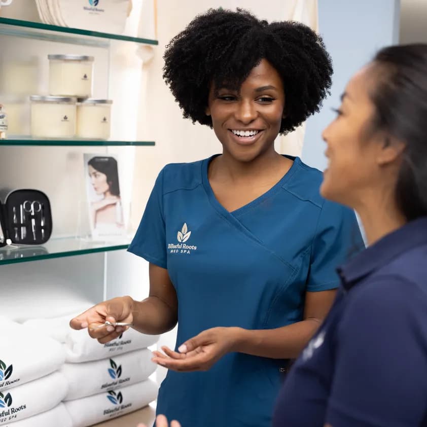 Spa staff wearing branded uniforms with custom logos talk near shelves of promotional merchandise and resale products.