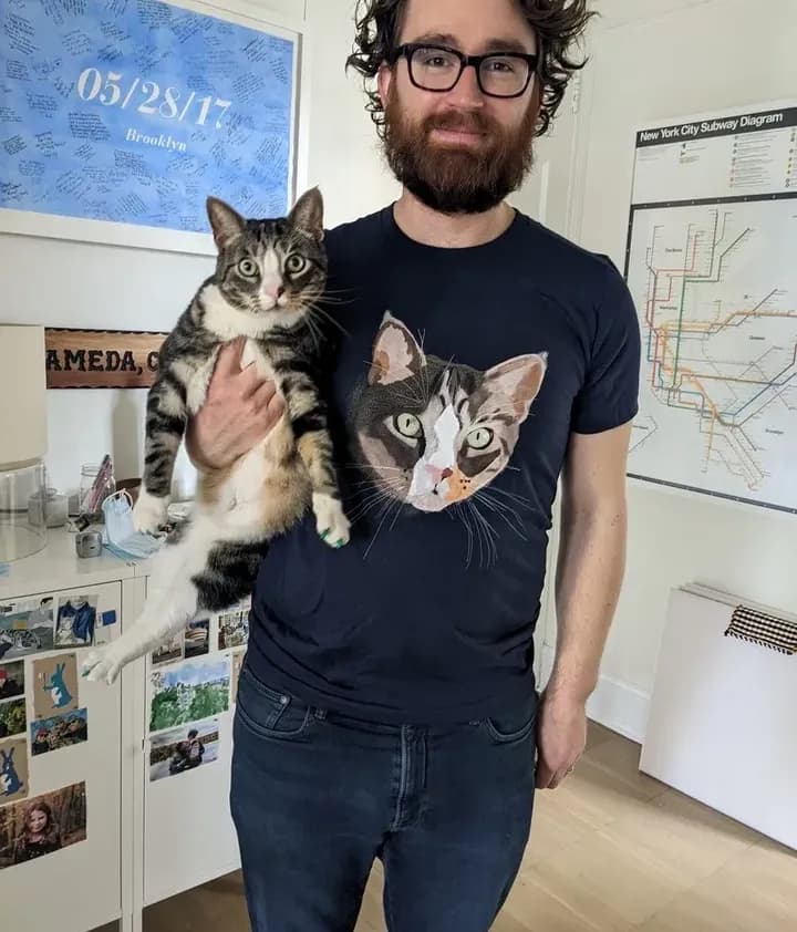Man wearing a custom printed t-shirt with his cat’s face while holding his matching pet.