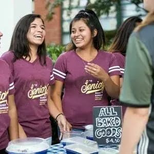 Group of students wearing matching custom "Senior" t-shirts at a bake sale stand.