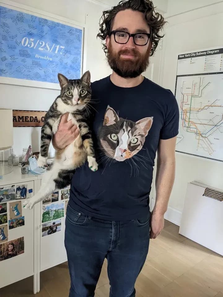 Man wearing a custom printed t-shirt with his cat’s face while holding his matching pet.