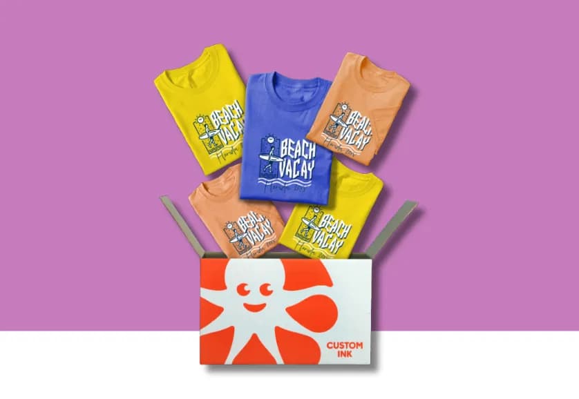 An open Custom Ink box bursting with colorful custom t-shirts in yellow, blue, and peach featuring a "Beach Vacay Florida 20XX" surfer graphic.