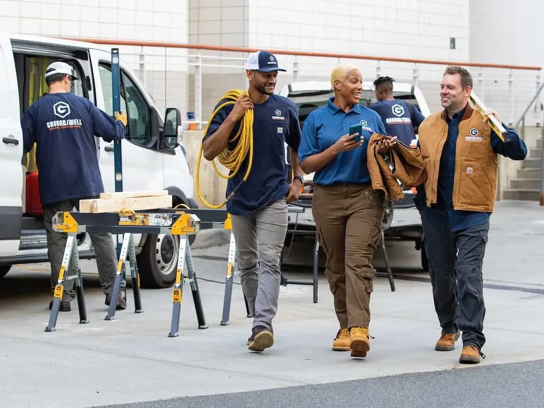 A group of contractors are walking on site with branded t-shirts, polos, and outerwear.