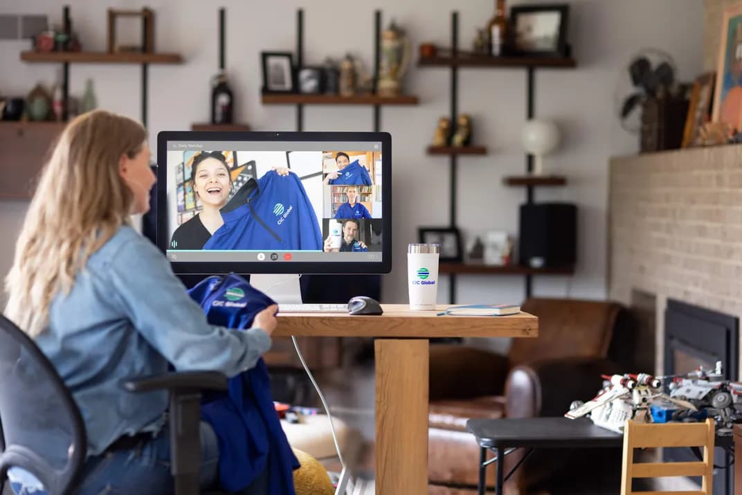 Employee on video call showing custom branded CIC Global apparel and drinkware during a virtual team meeting.