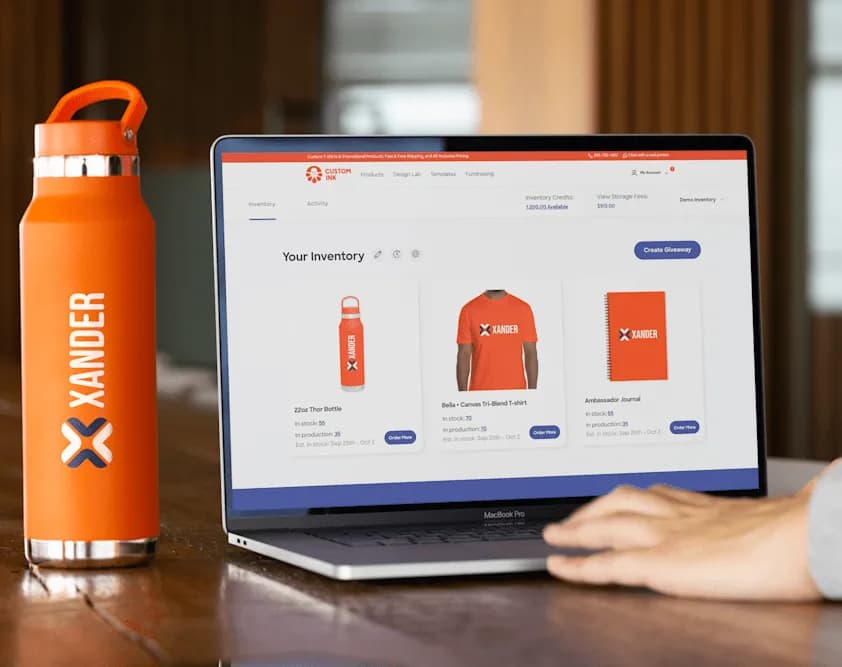 Xander branded water bottle site on table, adjacent to laptop displaying an online store for Xander branded products.