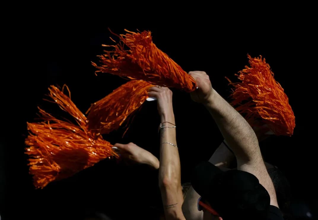 Abstract image of people cheering with red pom poms in a dark room.