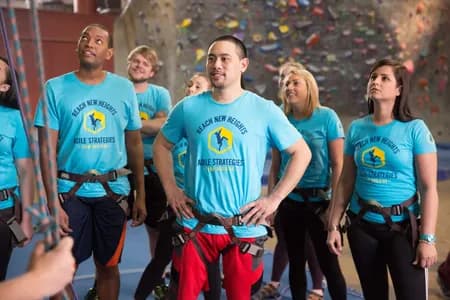A group of indoor rock climbers wear coordinating custom t-shirts in the gym.