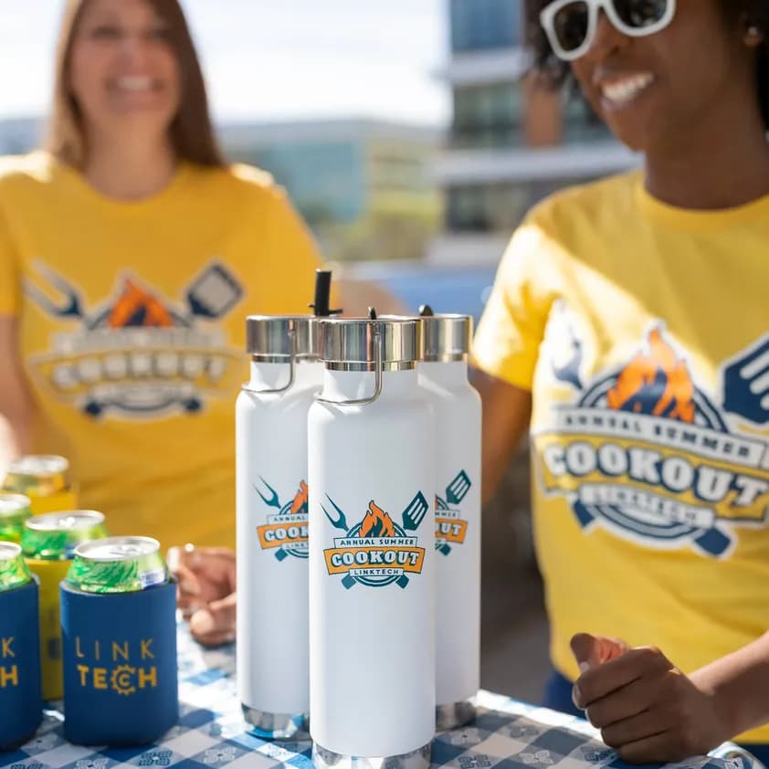 Employees wearing matching custom yellow cookout t-shirts with branded Link Tech drinkware and koozies at a summer event.