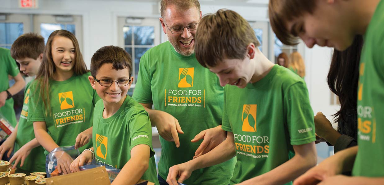 A church youth group works at a food pantry together in custom t-shirts.