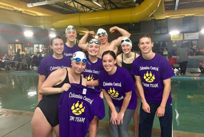 Swim team wearing custom apparel at pool deck with team name visible