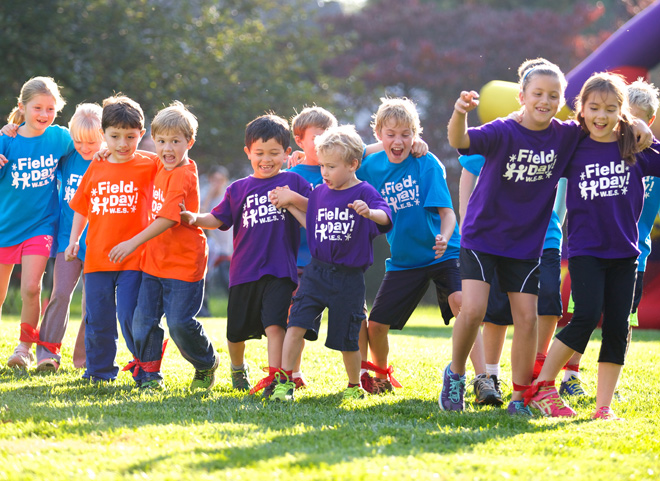 Elementary school students in colorful team shirts competing in field day events
