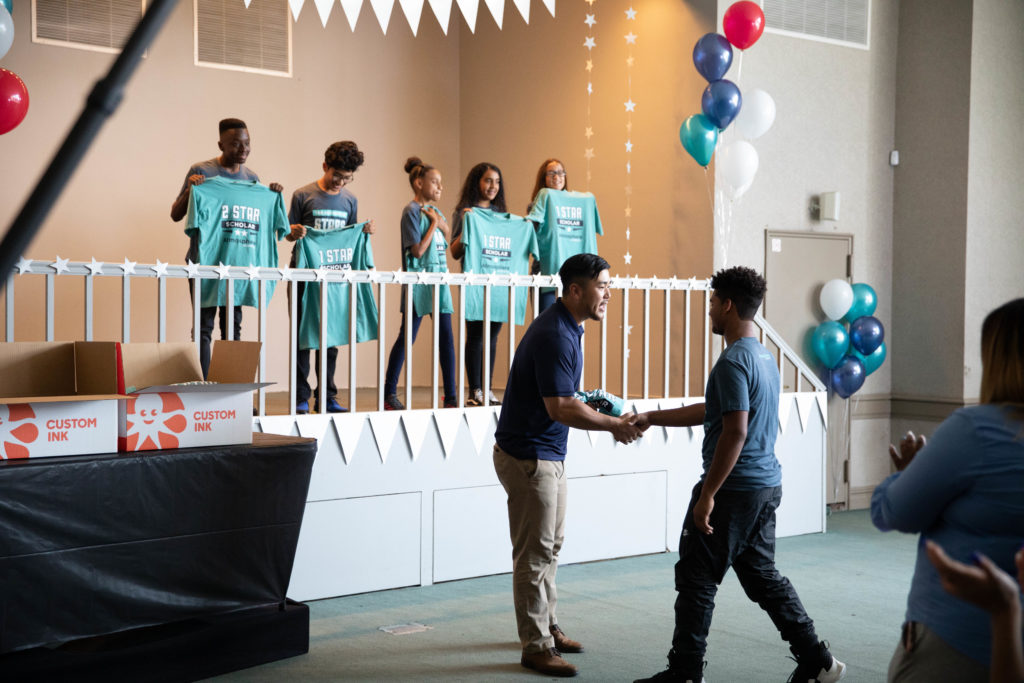A student receives a custom t-shirt from his administrator