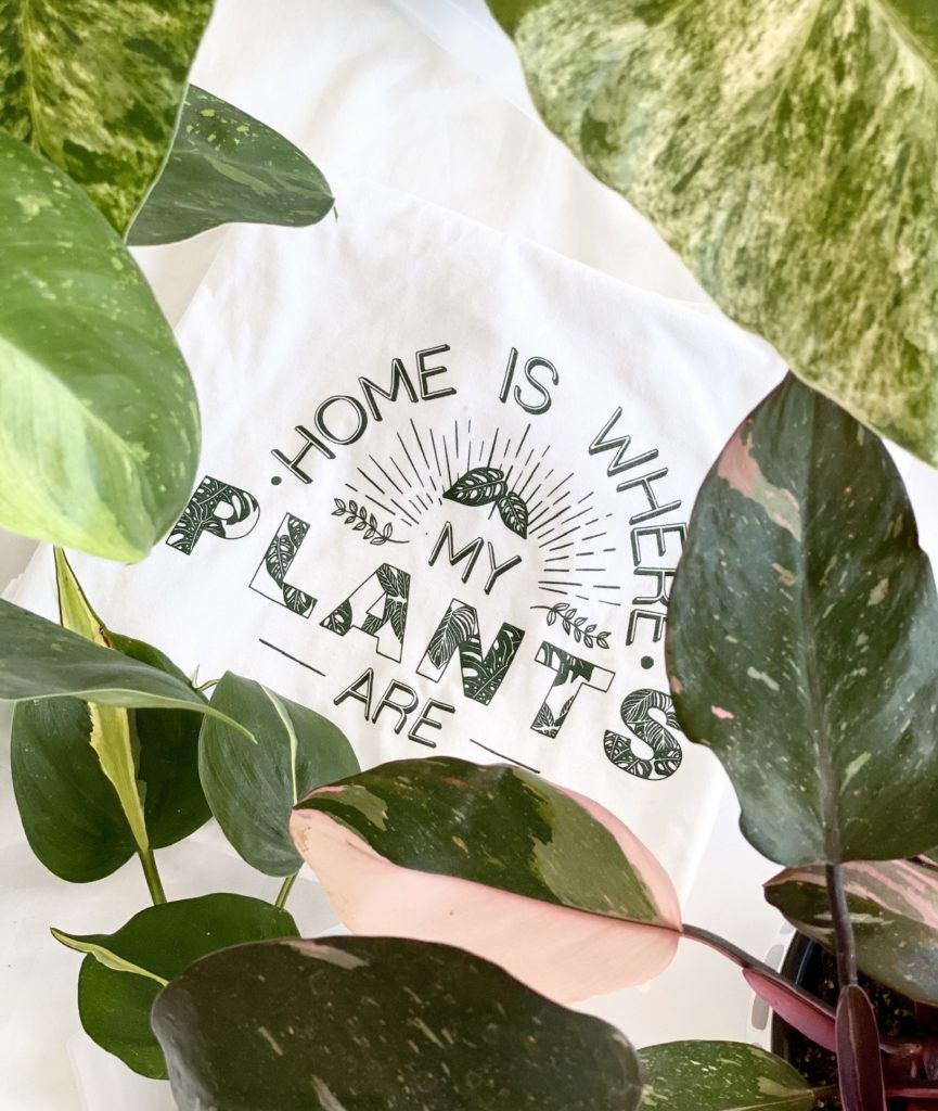 A folded shirt with Home is Where My Plants Are printed in green
