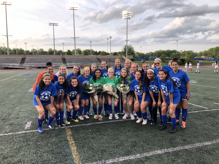 High school varsity soccer team wearing matching custom shirts for senior night on the field