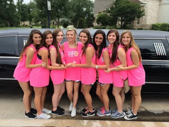 Group of friends wearing matching custom pink tank tops posing together for a birthday celebration.