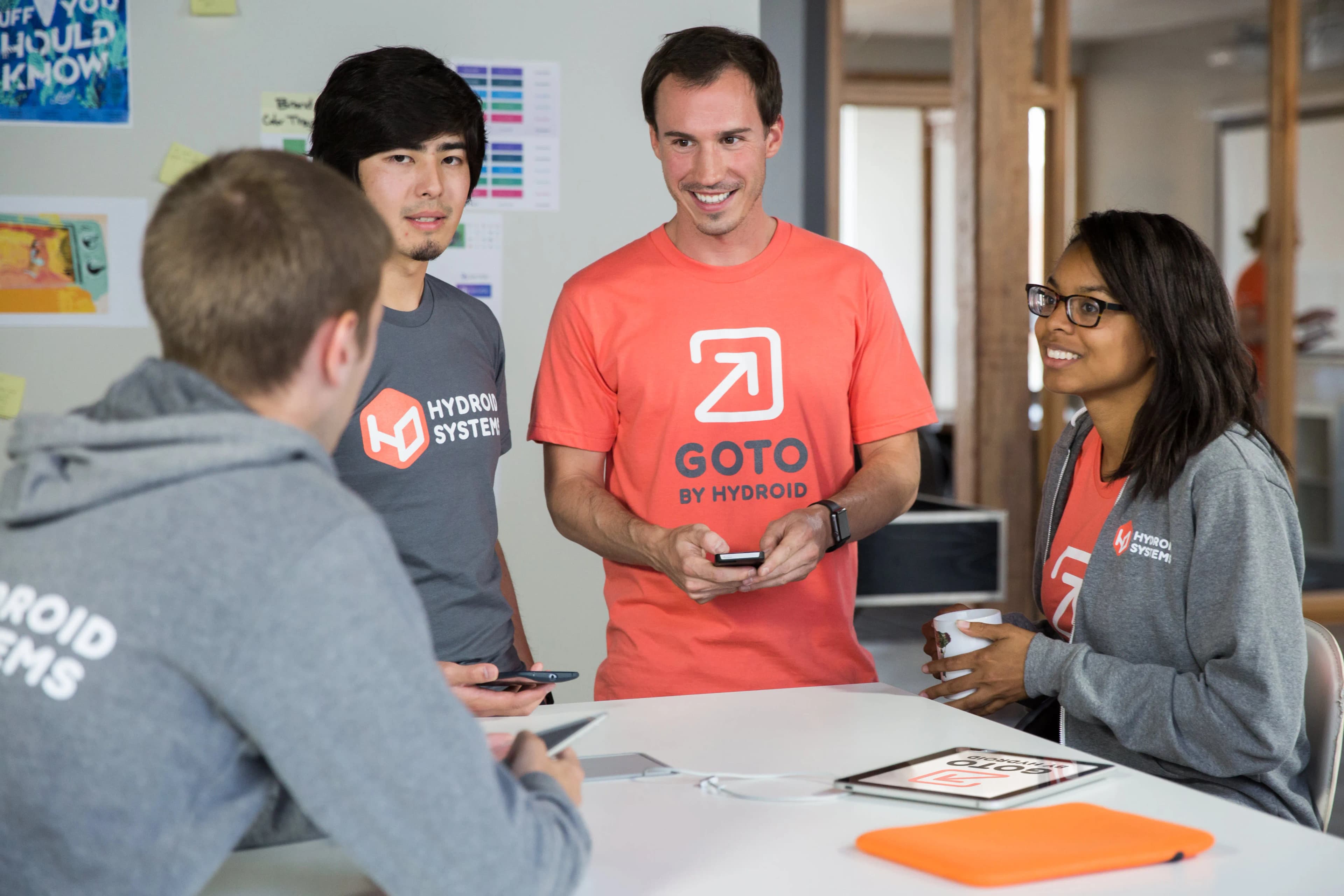 Coworkers around a conference table wearing branded logo uniforms.