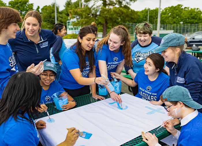 A group of students and faculty wearing custom t-shirts with their school mascot while working on a project.