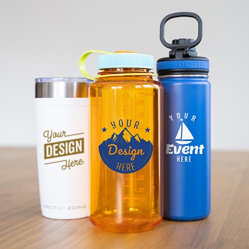 Two customized water bottles and one tumbler are standing up right on a table.